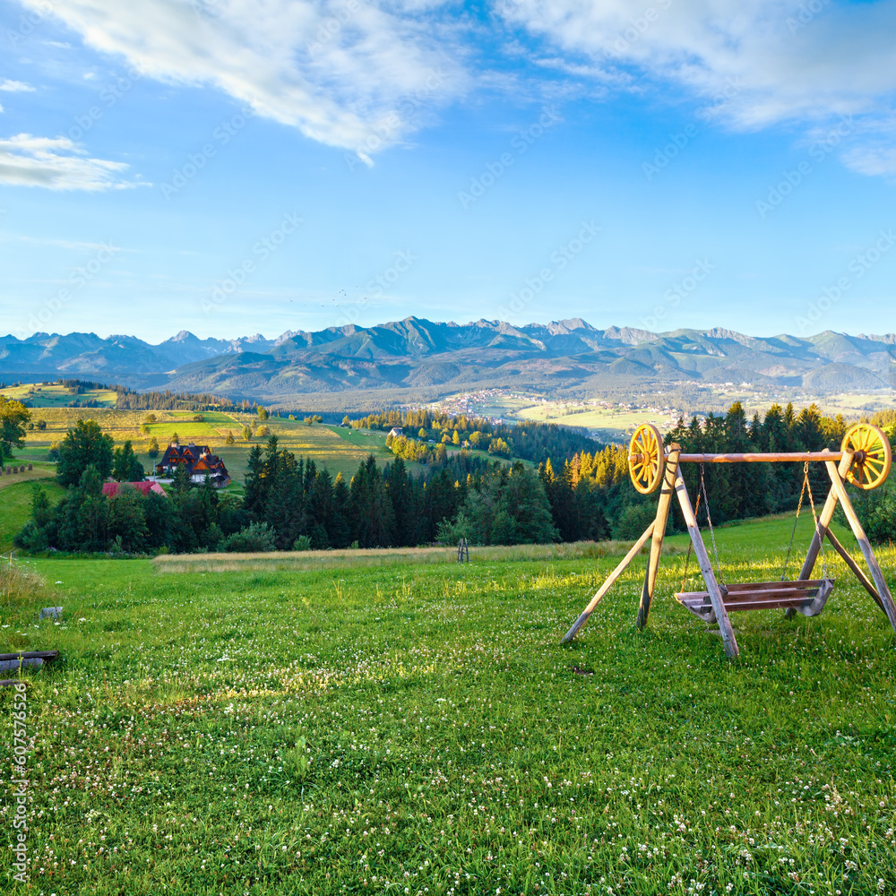 Summer morning hazy mountain village view and swing in front (Tatra range behind, Gliczarow Gorny, Poland)