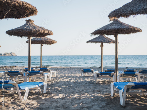 Mediterranean beach with straw umbrellas and blue sunbeds photo