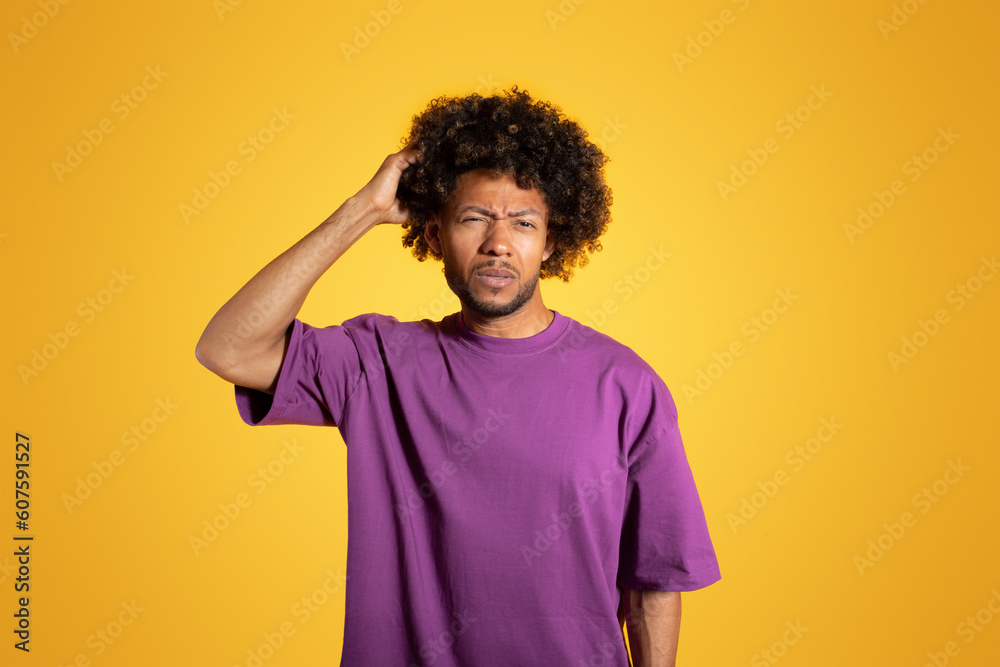 Sad pensive mature black curly guy in purple t-shirt thinking and scratching head Sad pensive mature black curly guy in purple t-shirt thinking and scratching head