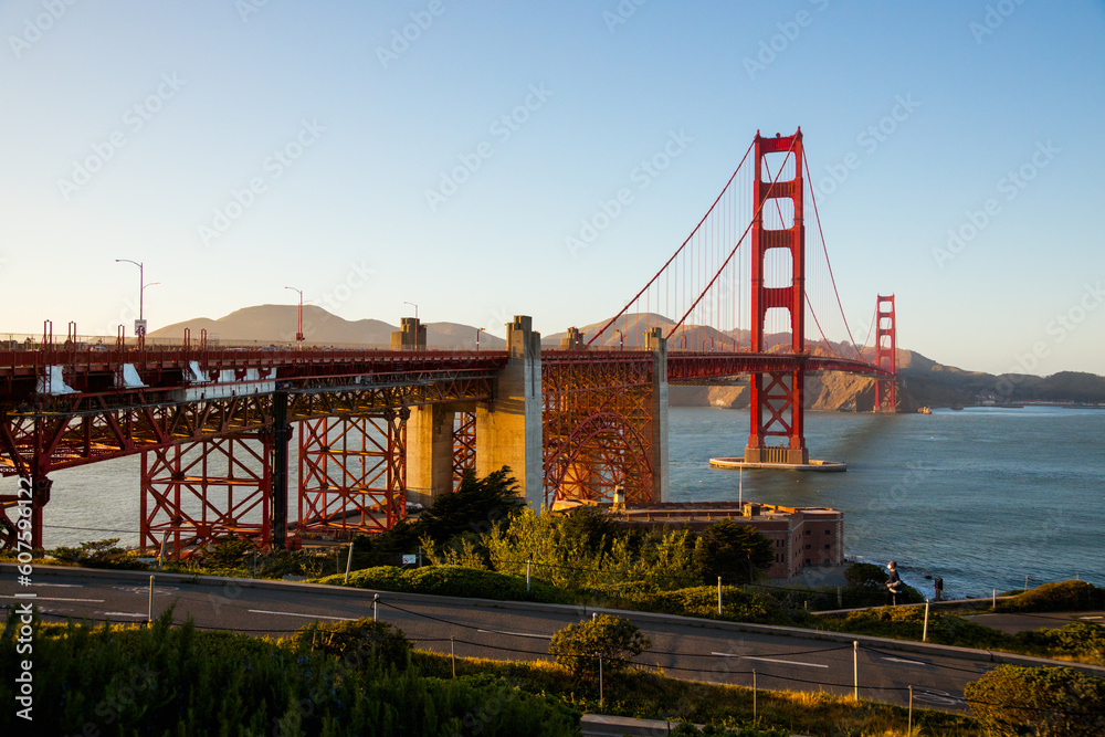 View of Golden Gate Bridge with a blue sky, lit by sunset. San Francisco Bay area.