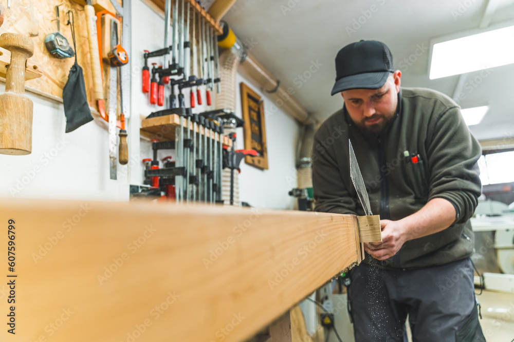 Caucasian carpenter using a tenon saw and cutting wood in his workshop, medium shot. High quality photo Caucasian carpenter using a tenon saw and cutting wood in his workshop, medium shot. High quality photo