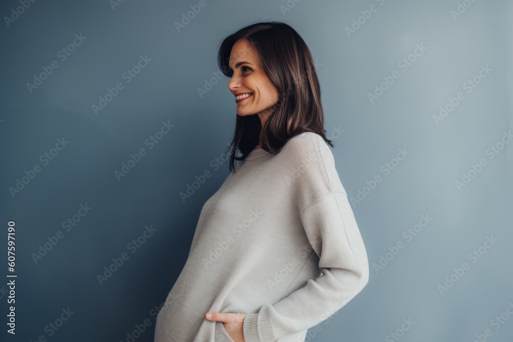 Portrait of a smiling young woman in sweater standing against grey background Portrait of a smiling young woman in sweater standing against grey background