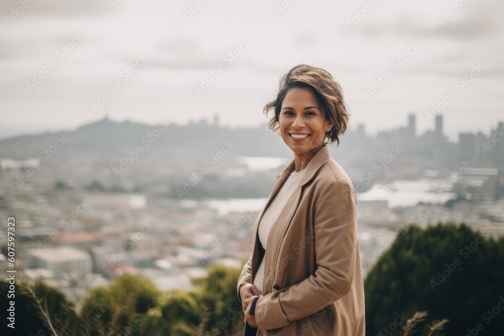 Portrait of a beautiful young woman smiling and looking at the camera while standing on a rooftop with a view of the city Portrait of a beautiful young woman smiling and looking at the camera while standing on a rooftop with a view of the city