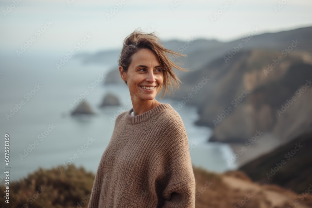 Portrait of a smiling woman standing on a cliff and looking at the sea Portrait of a smiling woman standing on a cliff and looking at the sea