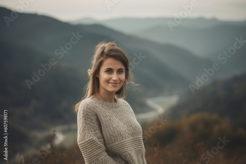 Portrait of a beautiful young woman in a sweater on a background of mountains