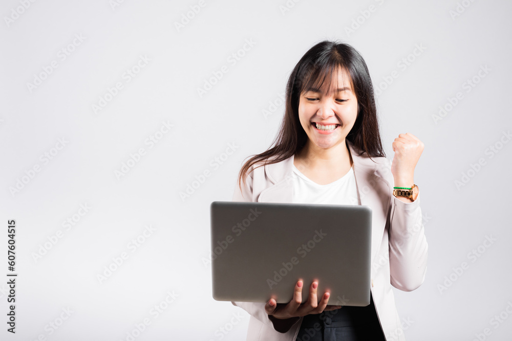 Woman smiling confident holding using laptop computer and excited celebrating success, Portrait excited happy Asian young female person say yes to win studio shot isolated on white background Woman smiling confident holding using laptop computer and excited celebrating success, Portrait excited happy Asian young female person say yes to win studio shot isolated on white background