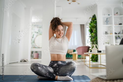 One young woman caucasian female yoga stretching practice at home online via laptop computer internet instructions course