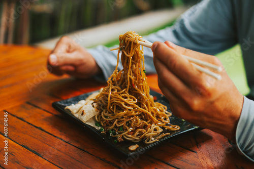 A man eats noodles. Asian noodles with vegetables