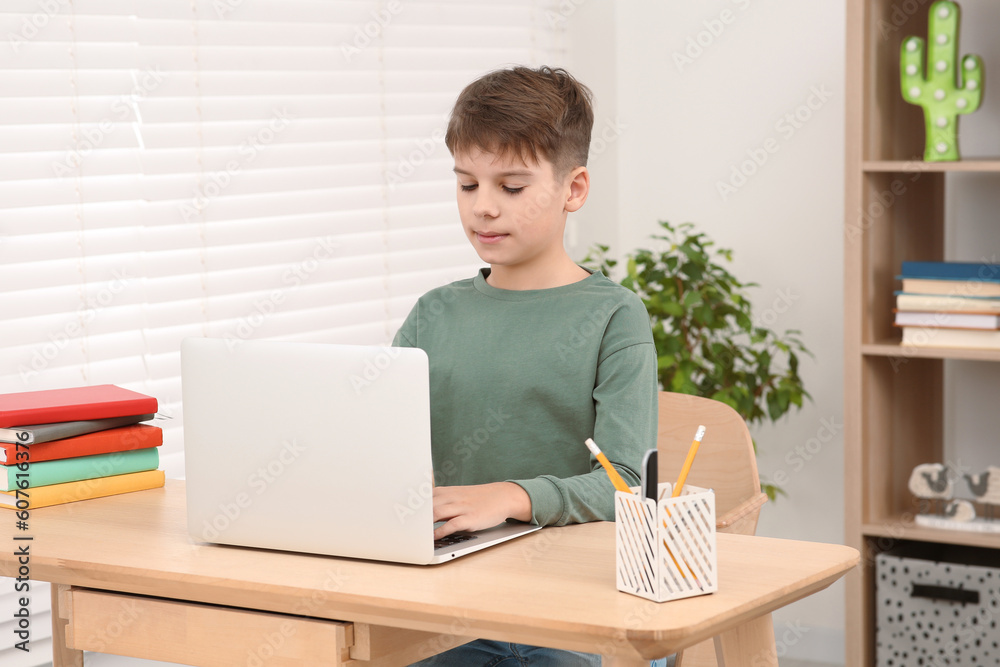 Boy using laptop at desk in room. Home workplace Boy using laptop at desk in room. Home workplace
