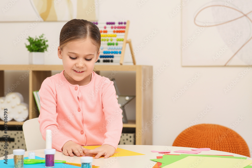 Cute little girl making colorful paper card at desk in room. Home workplace Cute little girl making colorful paper card at desk in room. Home workplace