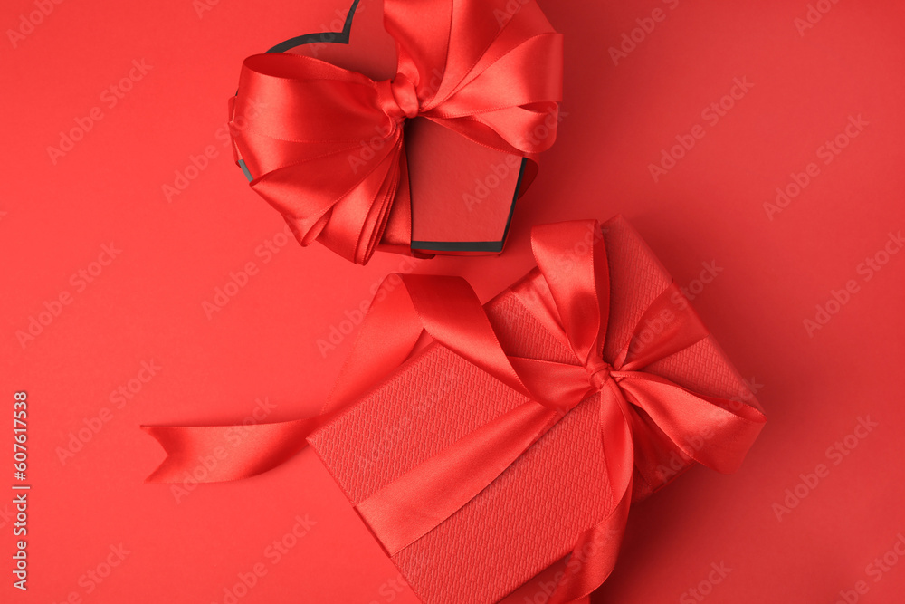 Beautiful gift boxes with bows on red background, flat lay Beautiful gift boxes with bows on red background, flat lay