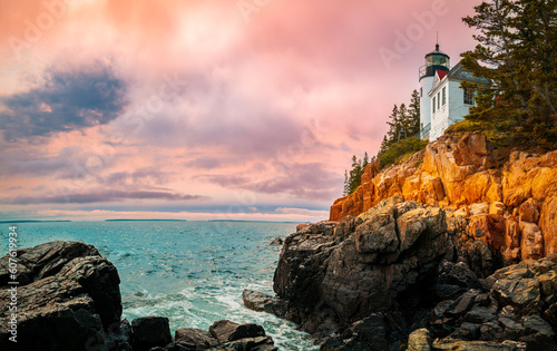 Sunset over the lighhouse on the cliff. Dramatic seascape with Bass Harbor Head Light Station in Tremont, Acadia National Park, Maine photo