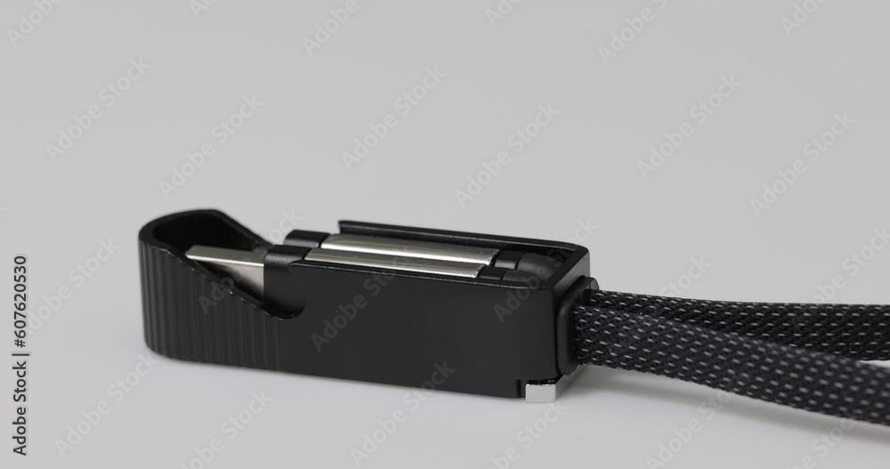 Textile Multifunctional USB Cable with Bottle Opener on White Rotating Plate. 4K Product Close-up Shot.