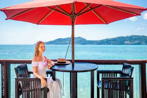 A young woman on summer vacation enjoys a delicious breakfast in a luxury hotel resort with a sea view. Girl enjoying her summer vacation. © TravelMedia