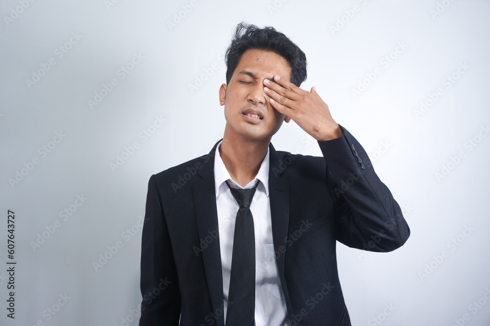 Tired exhausted Asian man wearing suit suffering from strong eye pain Tired exhausted Asian man wearing suit suffering from strong eye pain