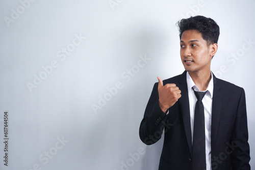 Young handsome Asian man wearing business clothes smiling and looking at the camera pointing with hands and fingers to the side.