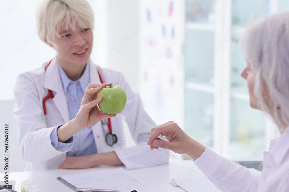 Obraz premium Dietitian advises senior woman eat fresh fruits in hospital