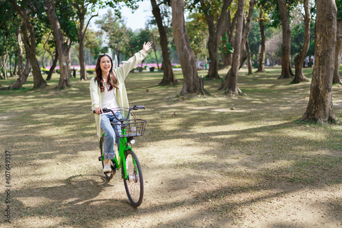 Women riding bicycle and raising arm with enjoying for relaxation and exercise for healthy in park