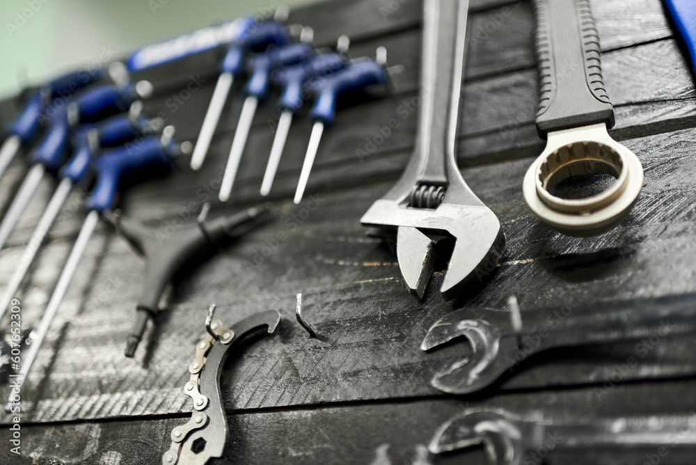 Fototapeta premium Wrenches and other hardware hanging on a tool board in a bicycle repair shop. Close up view with selective focus.