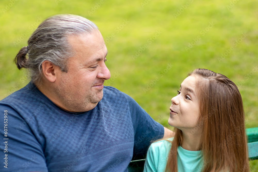 Father and daughter communicate, talk, in the park. Fatherhood, lifestyle, parenting, childhood and family life concept. Father and daughter communicate, talk, in the park. Fatherhood, lifestyle, parenting, childhood and family life concept.