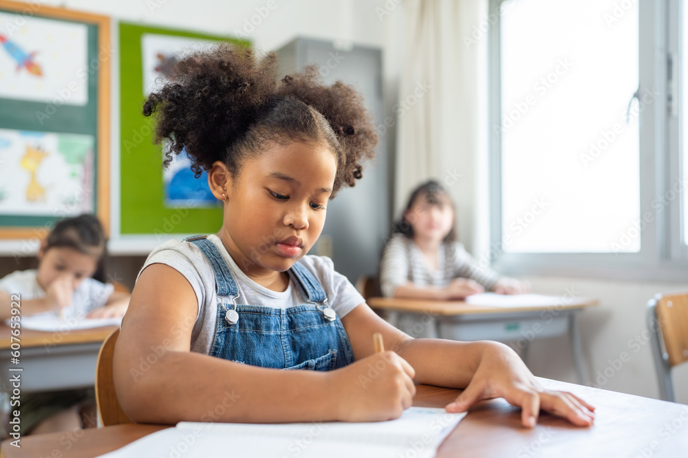 Students writing notebooks in the classroom. Junior Classroom with Diverse Group of Children Learning New Stuff. Students writing notebooks in the classroom. Junior Classroom with Diverse Group of Children Learning New Stuff.
