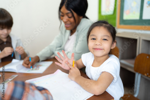 Portrait of little girl study art in classroom at school. She looking to camera and smile.