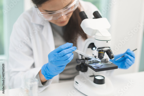 Medical development research laboratory, science young woman scientist in glasses, glove looking under microscope for test analysis samples in lab. Microbiology, analysing biochemicals for medicine