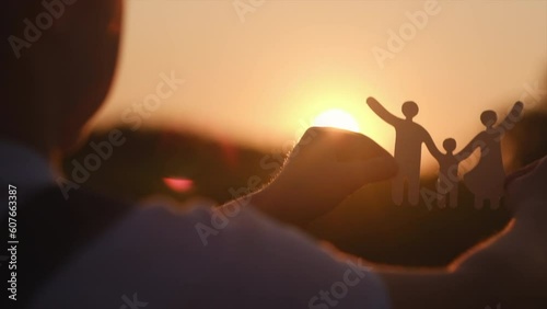 Side view of little girl holding paper family cutout on background amazing warm sunset or sunrise, family home, foster care, world mental health day, Autism support, budgeting cost of living concept