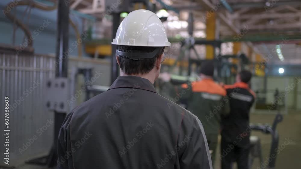 Follow of worker caucasian engineer man employee controls production process walking factory. Professional Heavy Industry Engineer Wearing Safety Uniform and Hard Hat in Metal Construction Manufacture Follow of worker caucasian engineer man employee controls production process walking factory. Professional Heavy Industry Engineer Wearing Safety Uniform and Hard Hat in Metal Construction Manufacture