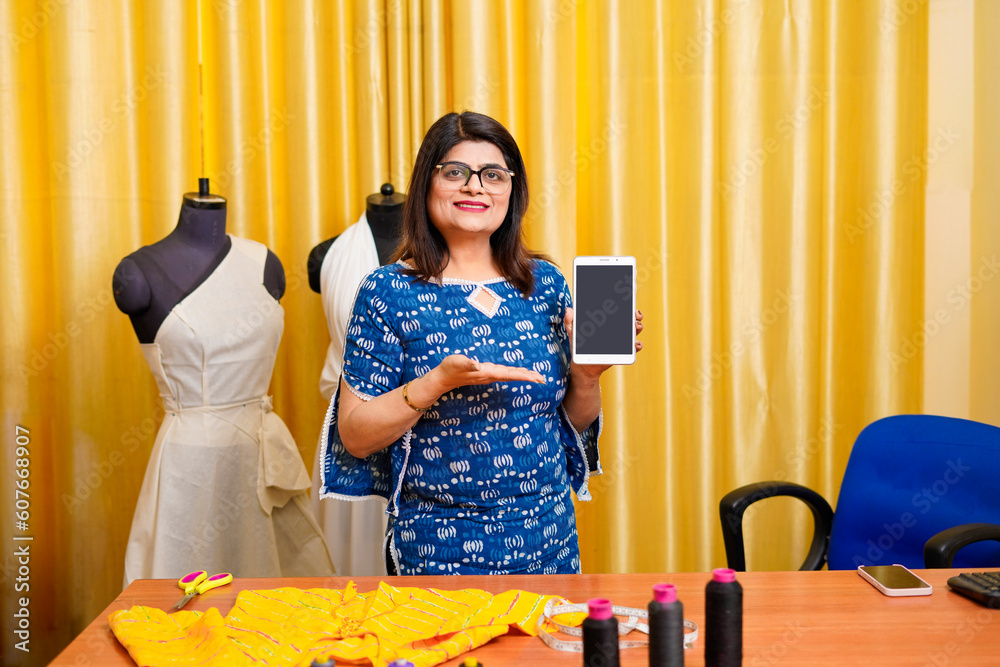 Young indian female fashion designer showing smartphone screen. Young indian female fashion designer showing smartphone screen.
