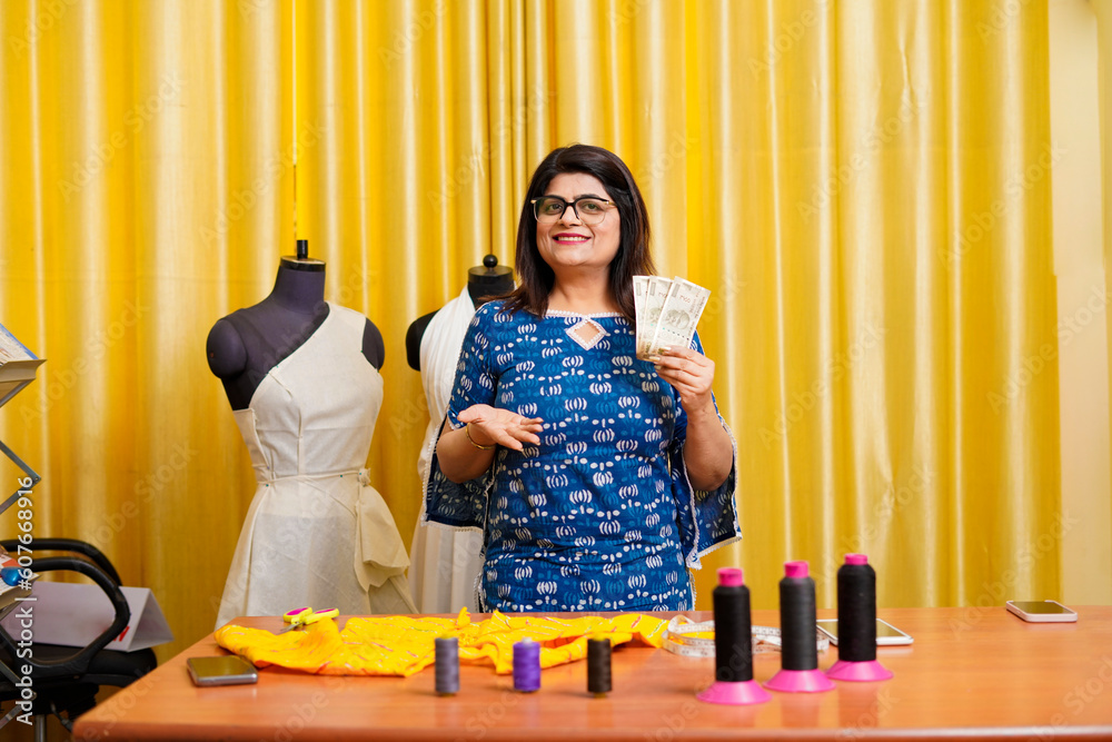 Indian female fashion designer showing money at her shop. Indian female fashion designer showing money at her shop.