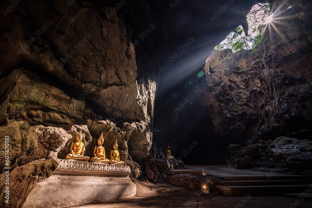 buddha in the ancient cave with beam of light and sunstar from the top (Phetchaburi Province, Thailand ). amazing natural landscape. popular attractions best famous tourist attractions