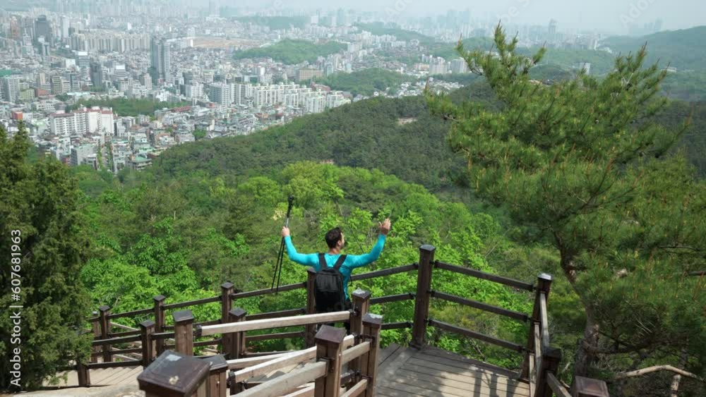 Excited Male Hiker Holding Trekking Poles On His Way Down On Wooden Staircase Trail Path In Gwanaksan Mountain - Overlooking Majestic Seoul City Skyline From the Top - Rising Arms Up Satisfied Excited Male Hiker Holding Trekking Poles On His Way Down On Wooden Staircase Trail Path In Gwanaksan Mountain - Overlooking Majestic Seoul City Skyline From the Top - Rising Arms Up Satisfied