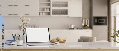 Workspace with white screen laptop computer mockup in modern apartment kitchen. © bongkarn