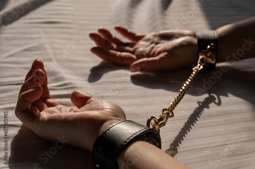 Close-up of woman's hands in leather handcuffs. Sex toy.