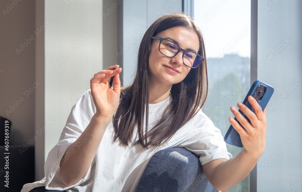 Student woman with smartphone and notepads at the window in the morning. Student woman with smartphone and notepads at the window in the morning.