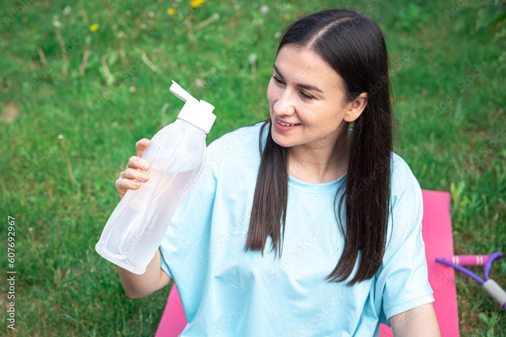A young woman drinking water after exercising outdoors. A young woman drinking water after exercising outdoors.