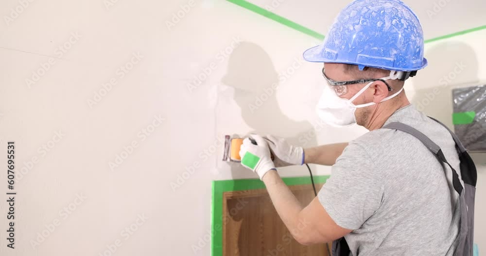 Finishing work abrasive in hand of master with wall putty. Leveling walls before painting Finishing work abrasive in hand of master with wall putty. Leveling walls before painting