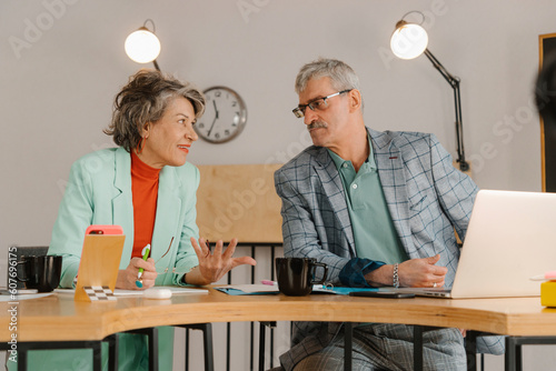 Senior businessman and woman communicate talking in studio photo