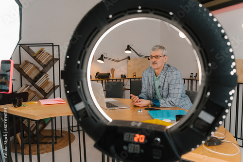 Businessman recording online class in studio seen through ringlight photo