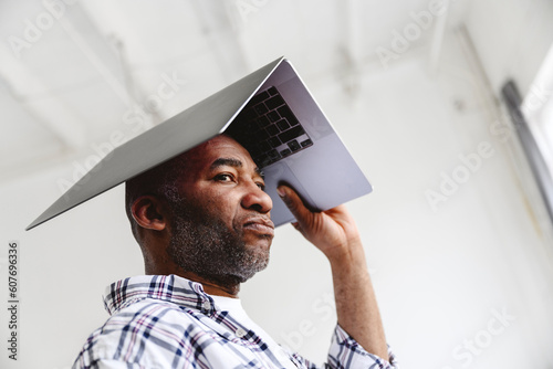 Bored businessman carrying laptop on head