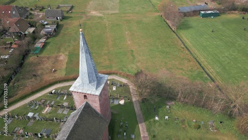 Aerial forward view of a church surrounded by greenery with a cemetery. Terschelling. Netherlands photo