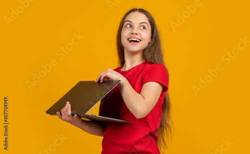 amazed child with laptop on yellow background