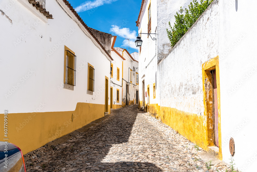 Cityscape of Evora with narrow street with typical houses painted in white. Alentejo, Portugal