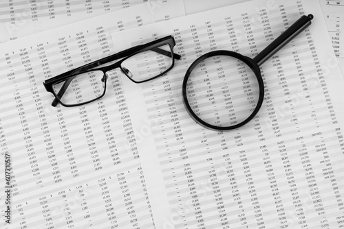 Magnifying glass and eye glasses on financial statement.