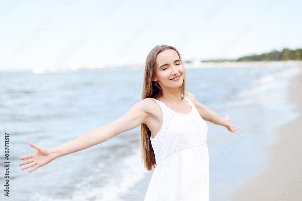Happy smiling woman in free happiness bliss on ocean beach standing with open hands. Portrait of a multicultural female model in white summer dress enjoying nature during travel holidays vacation outd Happy smiling woman in free happiness bliss on ocean beach standing with open hands. Portrait of a multicultural female model in white summer dress enjoying nature during travel holidays vacation outd