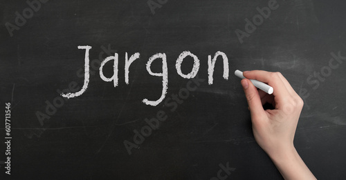 A woman's hand write text jargon with chalk on chalkboard