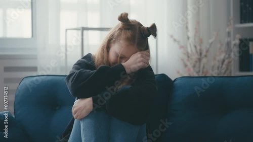 Teenage girl crying bitterly on couch, feeling depressed, adolescence, puberty photo