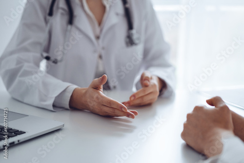 Doctor and patient discussing current health examination while sitting at the desk in clinic office, closeup. Medicine concept. © rogerphoto