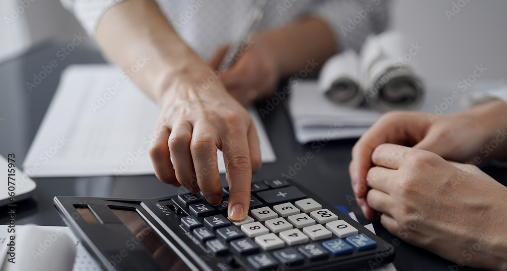 Woman accountant using a calculator and laptop computer while counting taxes for a client. Business audit and finance concepts. Woman accountant using a calculator and laptop computer while counting taxes for a client. Business audit and finance concepts.